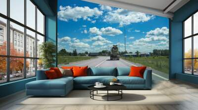 A truck is driving down a road with a blue sky in the background Wall mural