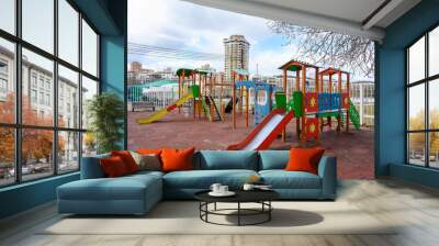 An empty playground in early spring in March against the background of high-rise buildings. Wall mural