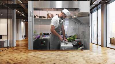 Male head chef prepare tasty fresh dish. Man cook meal restaurant kitchen. Young adult person work at cafe cuisine wear white hat. Guy make diet lunch food. Culinary worker job. Cookery staff uniform. Wall mural