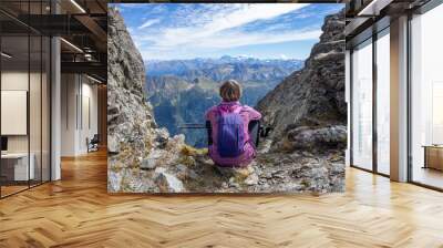 The girl is sitting on the pass against the backdrop of mountain peaks. Beautiful mountain landscape for recreation, travel and a healthy lifestyle. On the back plan is the summit of Elbrus. Caucasus, Wall mural