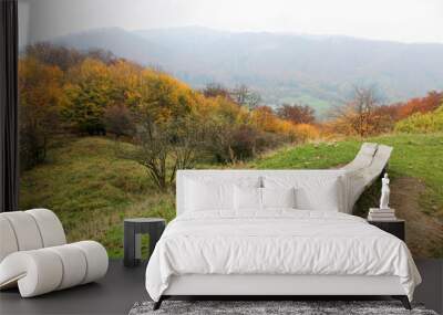 romantic wooden bench with the view to the hills with autumn colorful forest landscape Wall mural