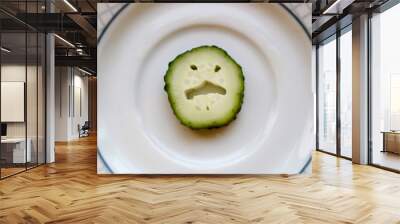 slice of funny angry cucumber face on plate background Wall mural