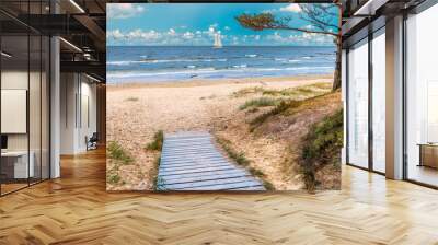 Wooden walkway leading to sandy beach of the Baltic Sea, on horizon one can sea white sport sailboat Wall mural