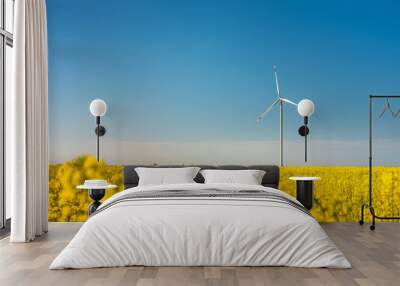 a lot of flowers of rapeseed field with view to isolated wind generator under blue sky with copy space Wall mural