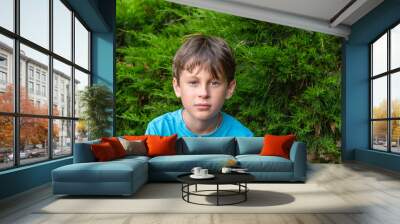 Portrait of a 9-year-old white European boy in the garden close-up. The child looks boldly into the camera Wall mural