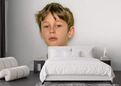 The child confidently looks directly into the camera . Portrait of a white Caucasian 9-year-old boy in a white T-shirt. Place to copy Wall mural