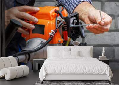  Technician, man in uniform is repairing a petrol mower on workbench. Small business. Wall mural