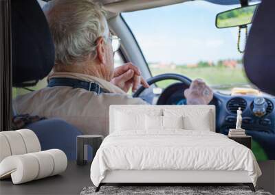 an elderly man is driving a car Wall mural