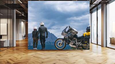 Back view of couple man and girl dressed in helmet and protective equipment for bikers is standing on top of the Dolomites mountains, his touring motorcycle on background, tourism concept, copy space Wall mural