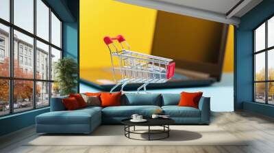 Toy grocery cart on the background of a laptop, concept on the topic of online shopping Wall mural