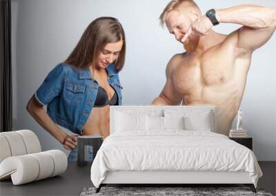 bearded muscular man shows perfect muscular abs of her sporty girlfriend sportswoman isolated on studio background Wall mural