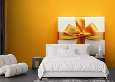 Elegant white gift box with golden ribbon on orange background Wall mural