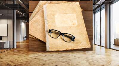 Old writing-books and glasses on a wooden table Wall mural