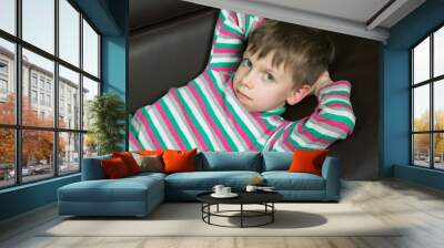 six year old boy lying on the couch and looking at the camera Wall mural