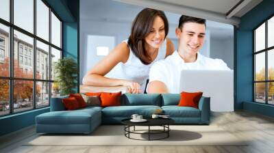 Happy modern couple working on laptop at home Wall mural