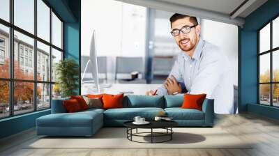 Male office worker sitting at desk Wall mural