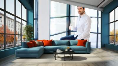 Young business man sitting on a stool in office Wall mural