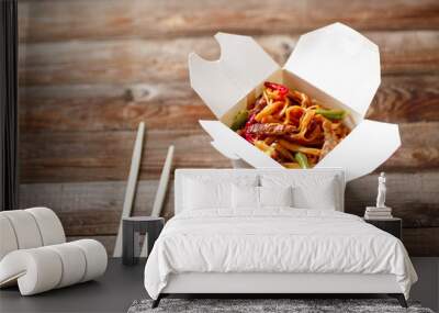 Noodles with pork and vegetables in take-out box on wooden table Wall mural