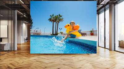 Boy at resort pool enjoys summer, splashing in buoy and floaties Wall mural