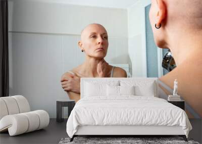 Contemplating woman ill of cancer facing her image without hair Wall mural