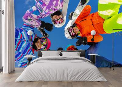 Four teenage girls look down with ski and winter sport outfit standing together smiling Wall mural