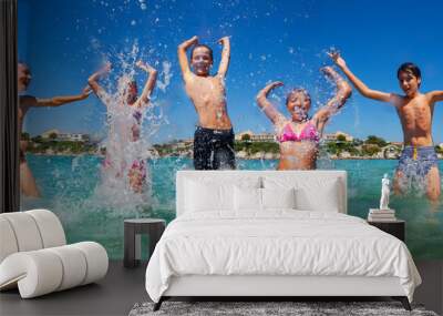 Friends jumping and splashing at shallow water Wall mural