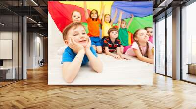 Happy boy playing under parachute with friends Wall mural