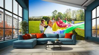 Happy boy waving colorful parachute with friends Wall mural