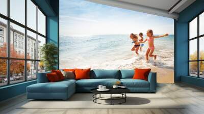 happy friends running along edge of sea in summer Wall mural