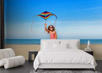 Happy little girls run with cute kite on the sand Wall mural