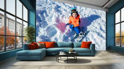 View from above of smiling little boy with ski and winter outfit Wall mural