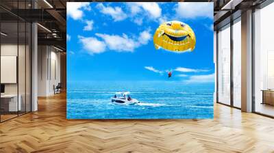 Parasailing water amusement. Flying on a parachute behind a boat on a summer holiday by the sea in the resort.  Wall mural