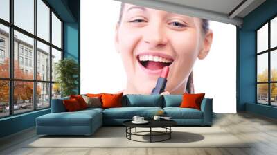 young laughing woman is applying cosmetics on her face and looki Wall mural