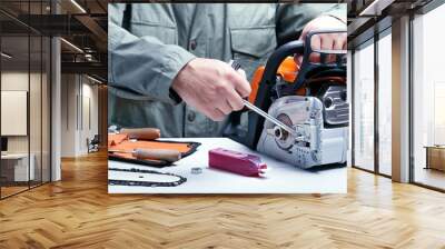 Repair of chainsaws,gasoline powered tools. Man repairing chainsaw. Wall mural