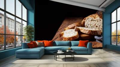 Rustic sourdough bread with cut slices on a wooden table. Panorama, black background with free space for text. Wall mural