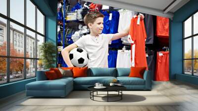 Boy with ball and red t-shirt in football store Wall mural