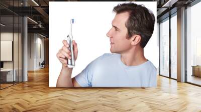 Happy man looks at electric toothbrush isolated Wall mural