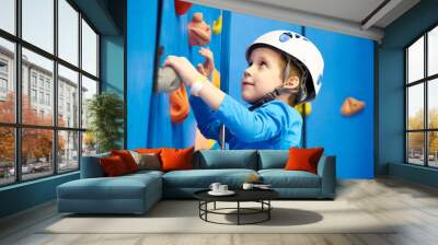 Little boy is climbing in sport park on blue wall Wall mural