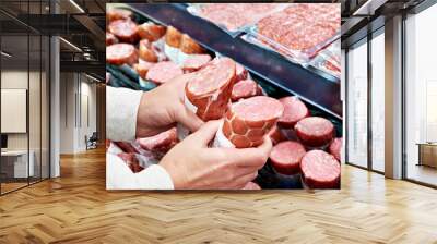 Sliced sausage in hands in store Wall mural