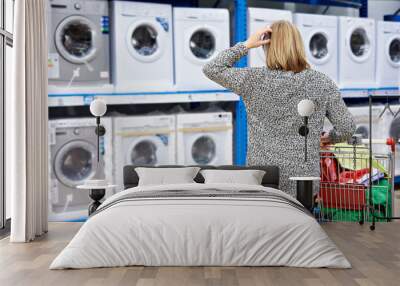 Woman chooses washing machine in shop of home appliances Wall mural