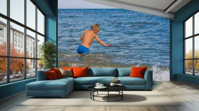 The boy is swimming in the sea without hiding joy. Wall mural