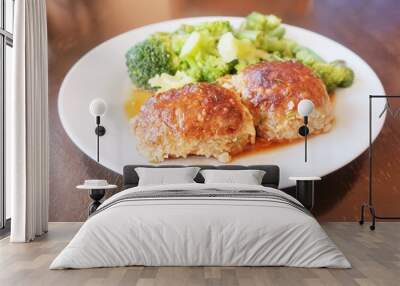 two juicy cutlets with sauce and broccoli on a white plate Wall mural