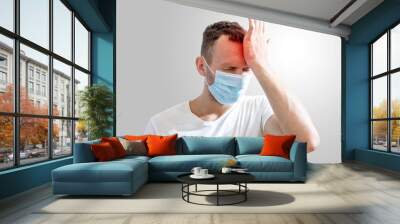 young man in medical mask holding his head in pain on gray background Wall mural