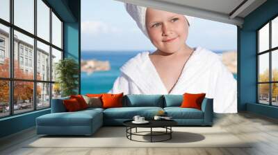 little girl with towel on head in white bathrobe on sea backgro Wall mural