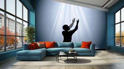 silhouette of a man in prayer raises his hands with rays coming Wall mural