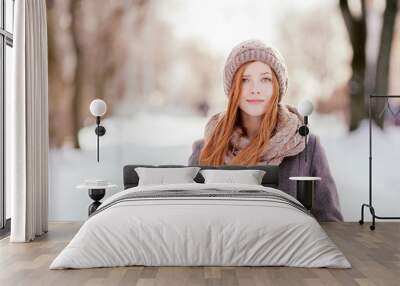 Beautiful redhead woman in grey coat strolling in winter park Wall mural