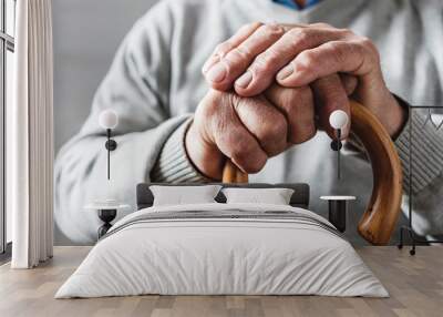 Hands of an elderly man resting on a walking cane Wall mural