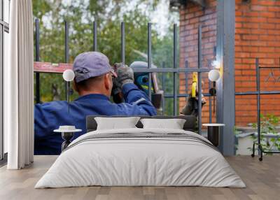 A team of construction workers install a metal fence around a new home. Wall mural