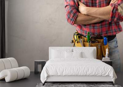 Worker man with tool belt near concrete or cement wall. Male hand and tools for house renovation Wall mural