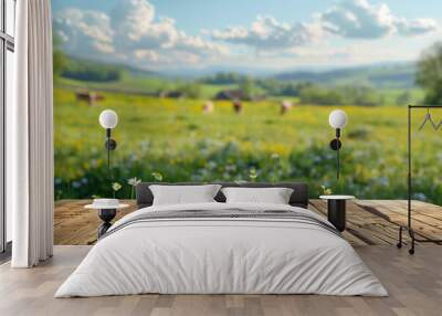 A wooden table is positioned in front of a vast green farm field and grazing cows on a sunny summer day, creating a podium for advertising the product Wall mural